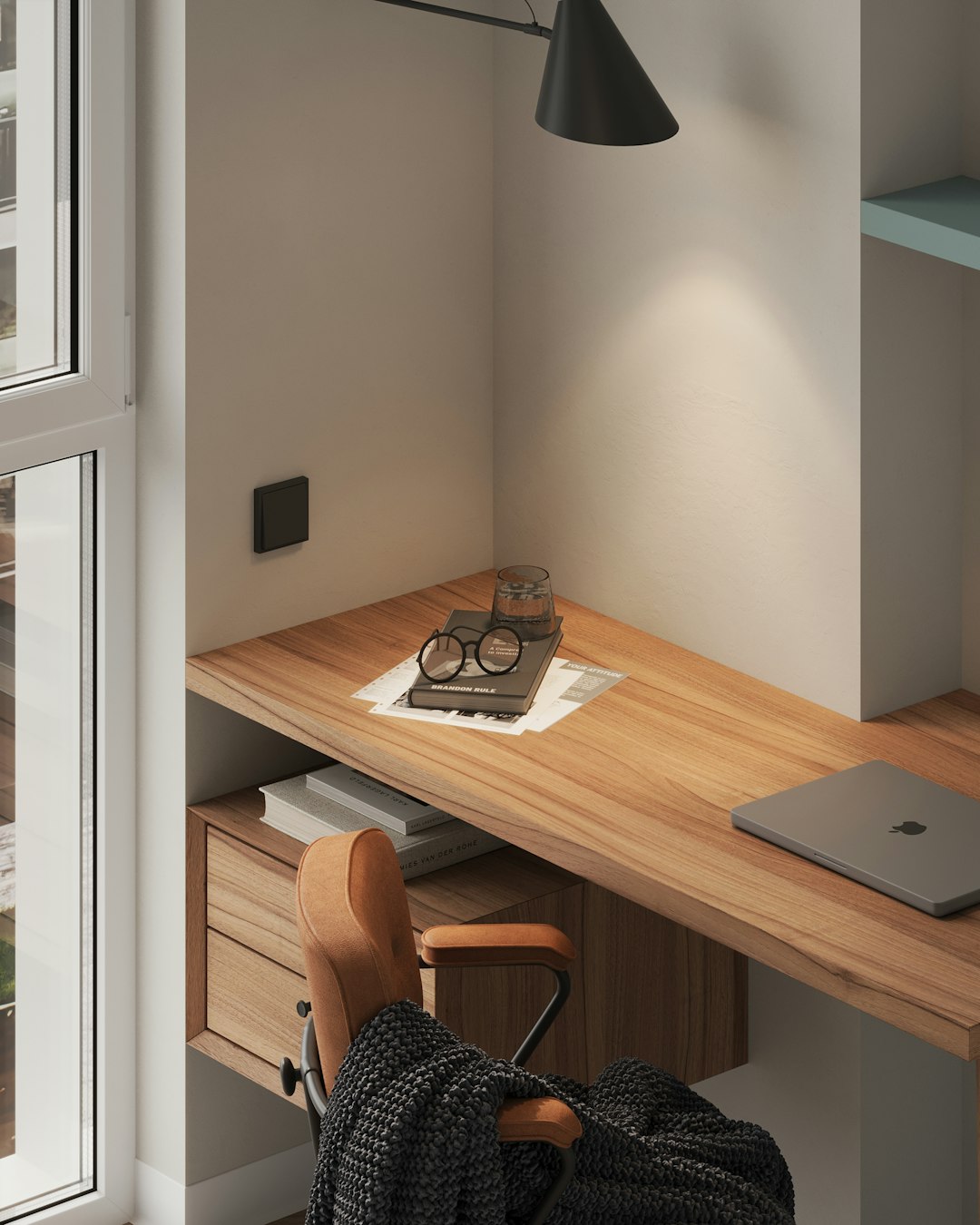 Compact apartment workspace with small wooden desk and laptop